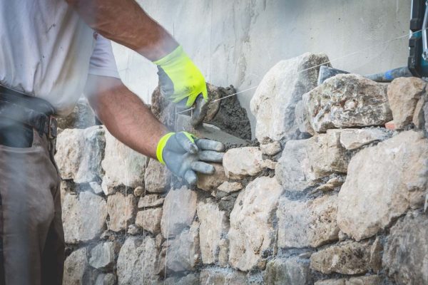 worker rides a stone wall on a traditional renovation site